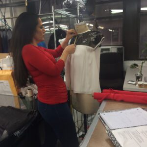 A woman in red shirt working on a dress.