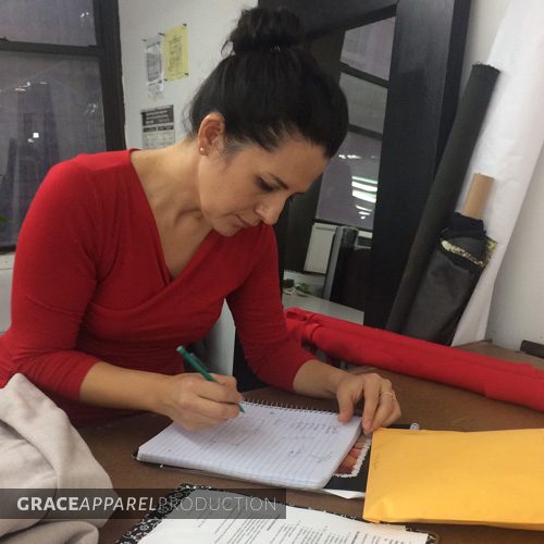 A woman in red shirt writing on paper.