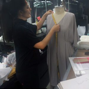 A woman is measuring the length of a dress.