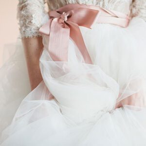 A woman in a white dress holding onto the pink ribbon