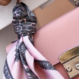 A close up of a bag with a scarf hanging on it